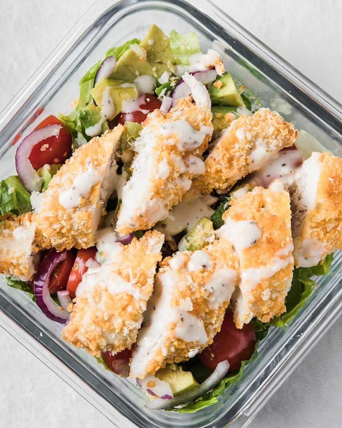 a glass lunch container with chicken strip salad