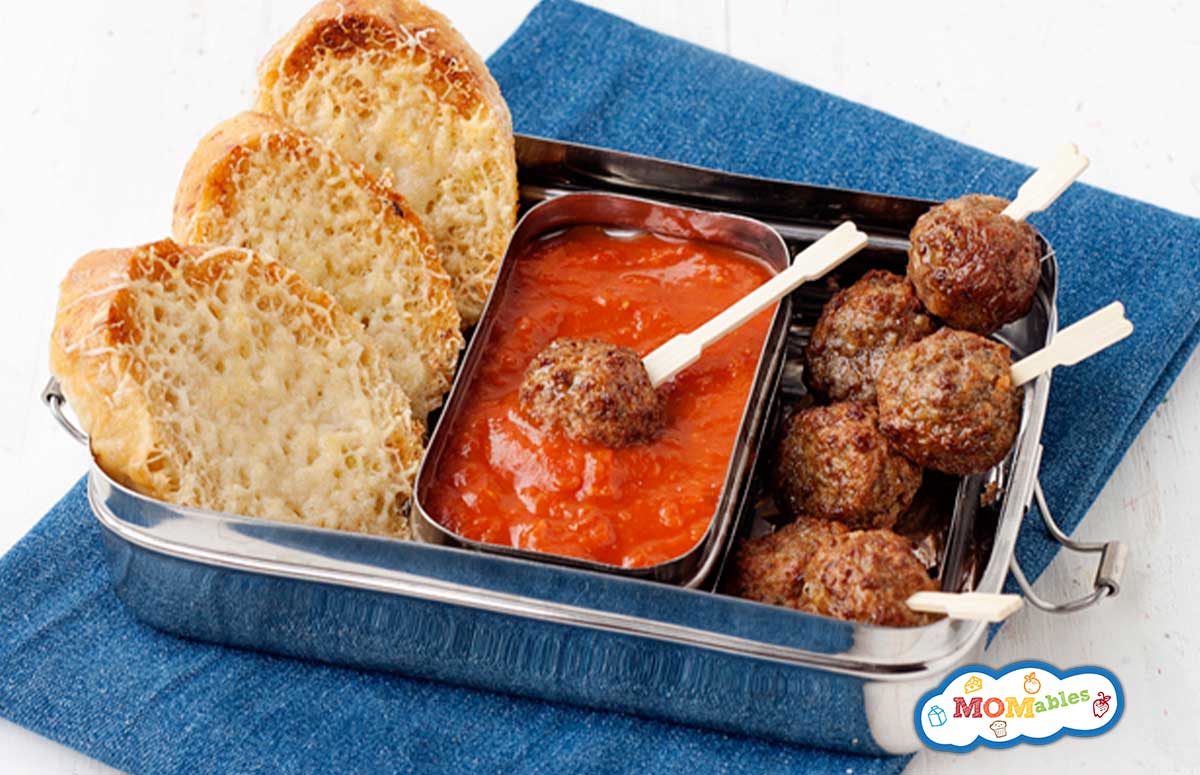 lunchbox with meatball skewers, tomato sauce and sliced bread