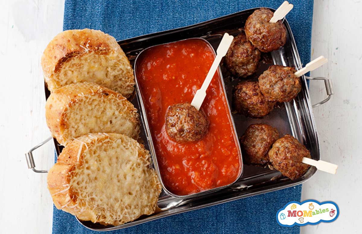 lunchbox with meatball skewers, tomato sauce and sliced bread