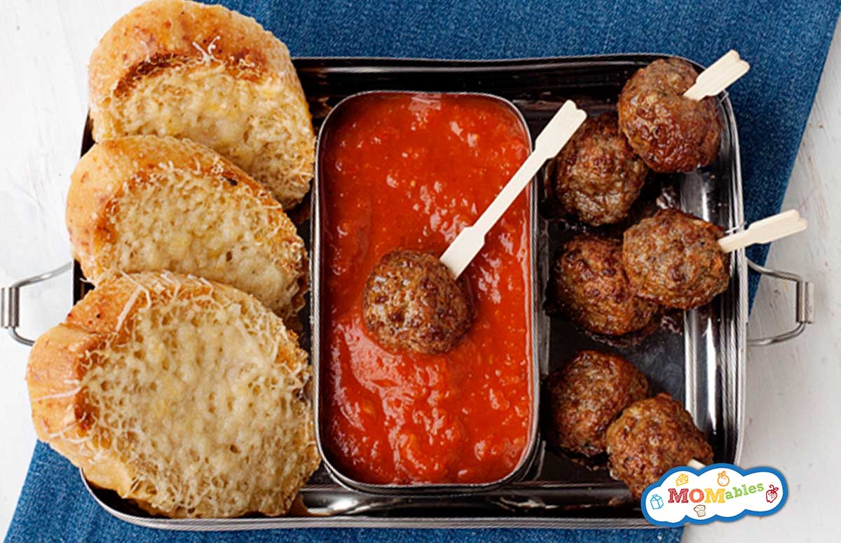 lunchbox with meatball skewers, tomato sauce and sliced bread
