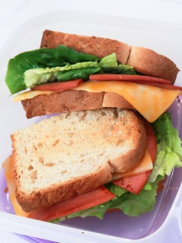 closeup of fried bologna sandwich with cheese, lettuce, mayo and toasted bread in a lunchbox