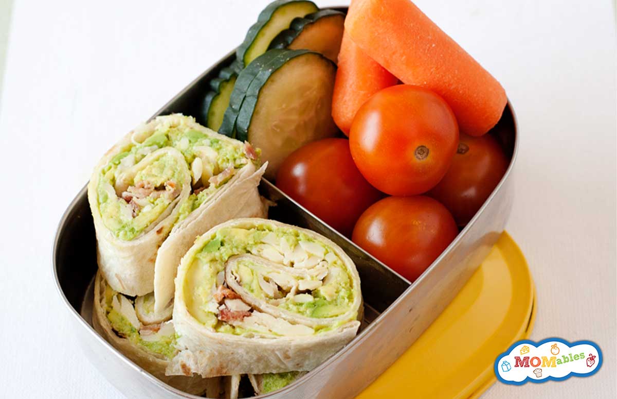 tortilla avocado pinwheels in a lunch box with veggies