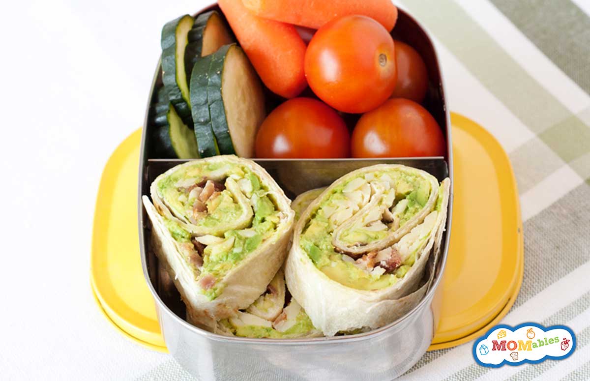 tortilla avocado pinwheels in a lunch box with veggies