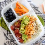 buffalo chicken and rice bowls in a lunch container with blueberries and carrot sticks