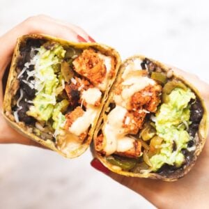 two hands holding halves of a chipotle chicken wrap