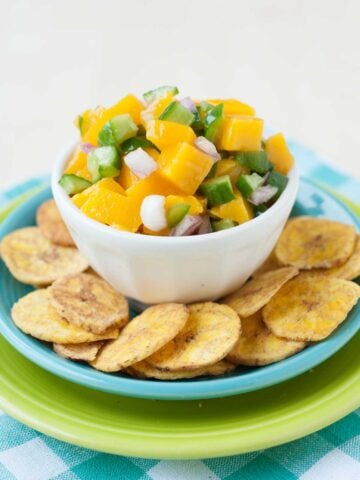 a bowl with salsa over a dish with baked plantain chips