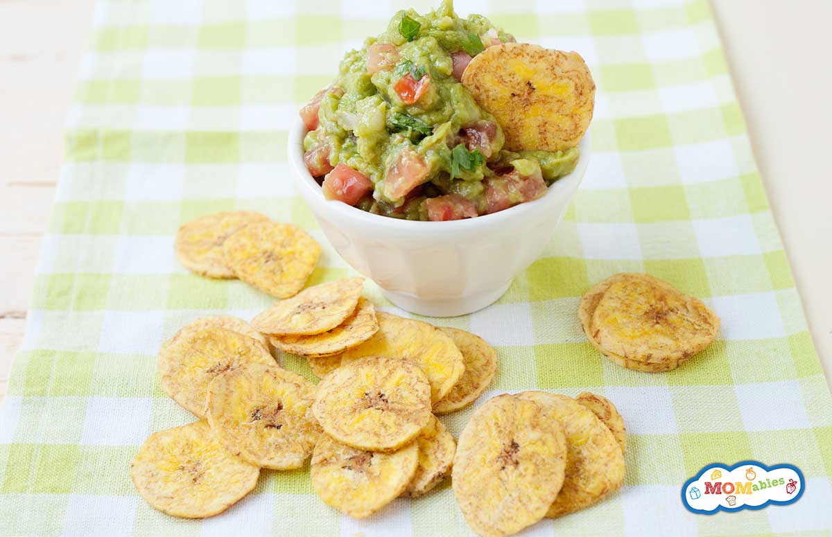 a bowl of guacamole and baked plantain chips around.