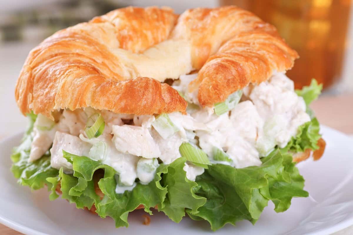 chicken salad croissant with a large lettuce leaf on the sandwich
