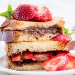 two halves of a nutella strawberry sandwich topped with strawberries