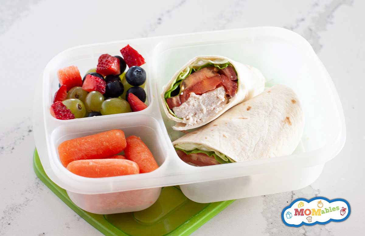 canned chicken wrap in a lunch container with veggies and fresh fruit