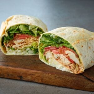 a chicken wrap cut in half on a cutting board