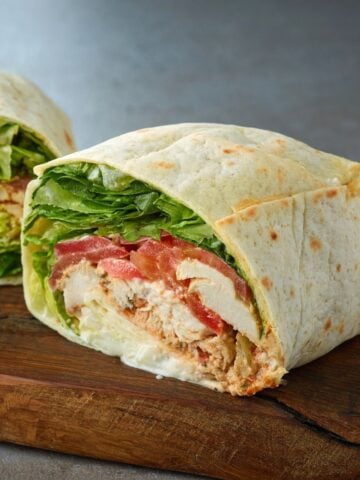 a chicken wrap cut in half on a cutting board