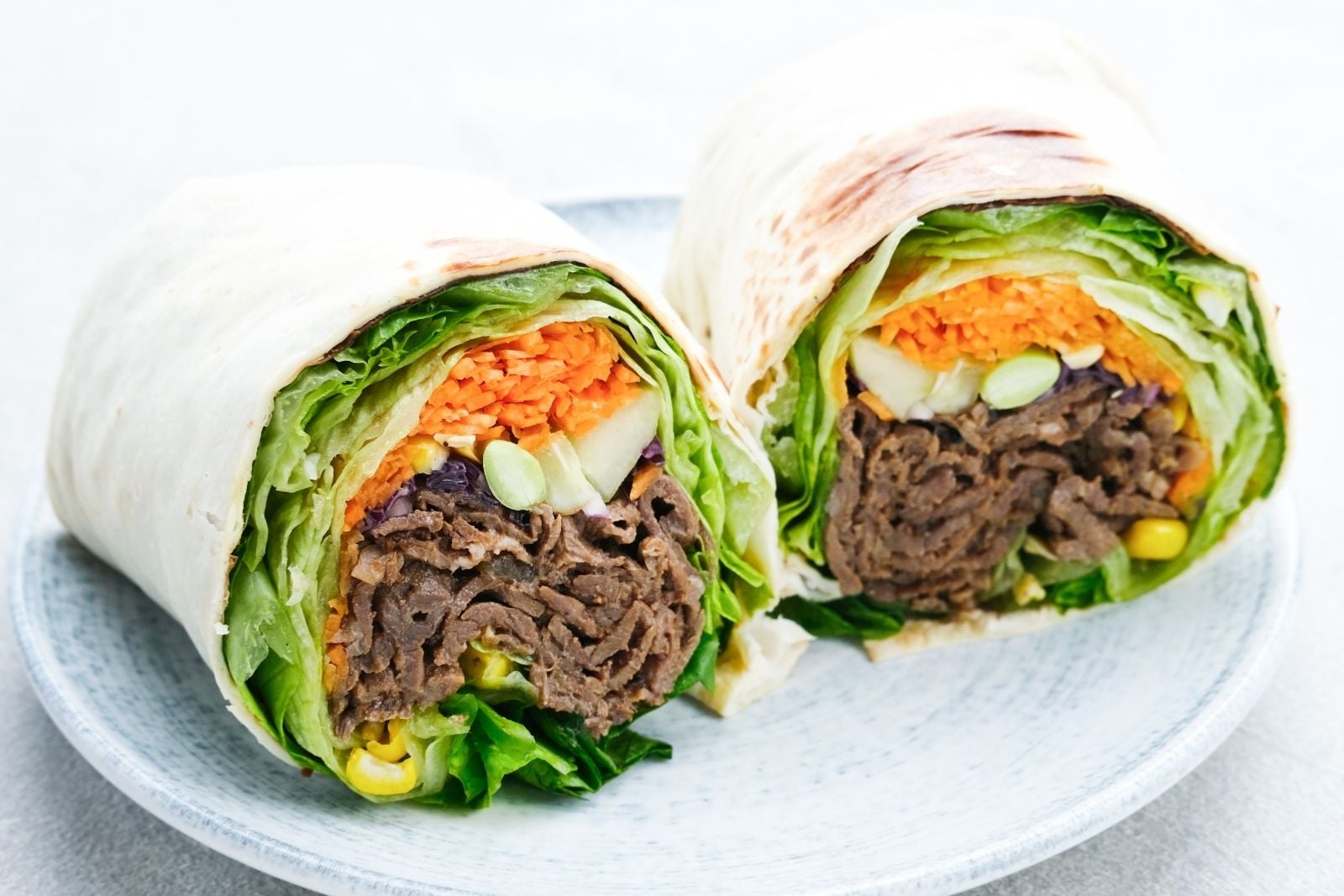 two halves of a roast beef and veggie wrap