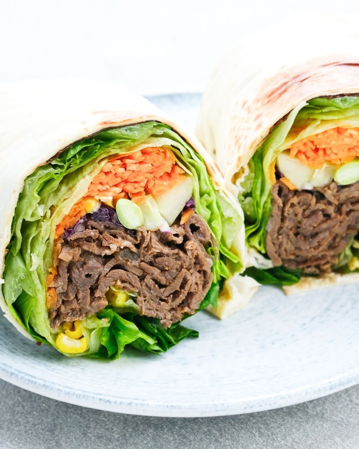 two halves of a roast beef and veggie wrap