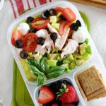a school lunch salad with tomatoes in a lunch container