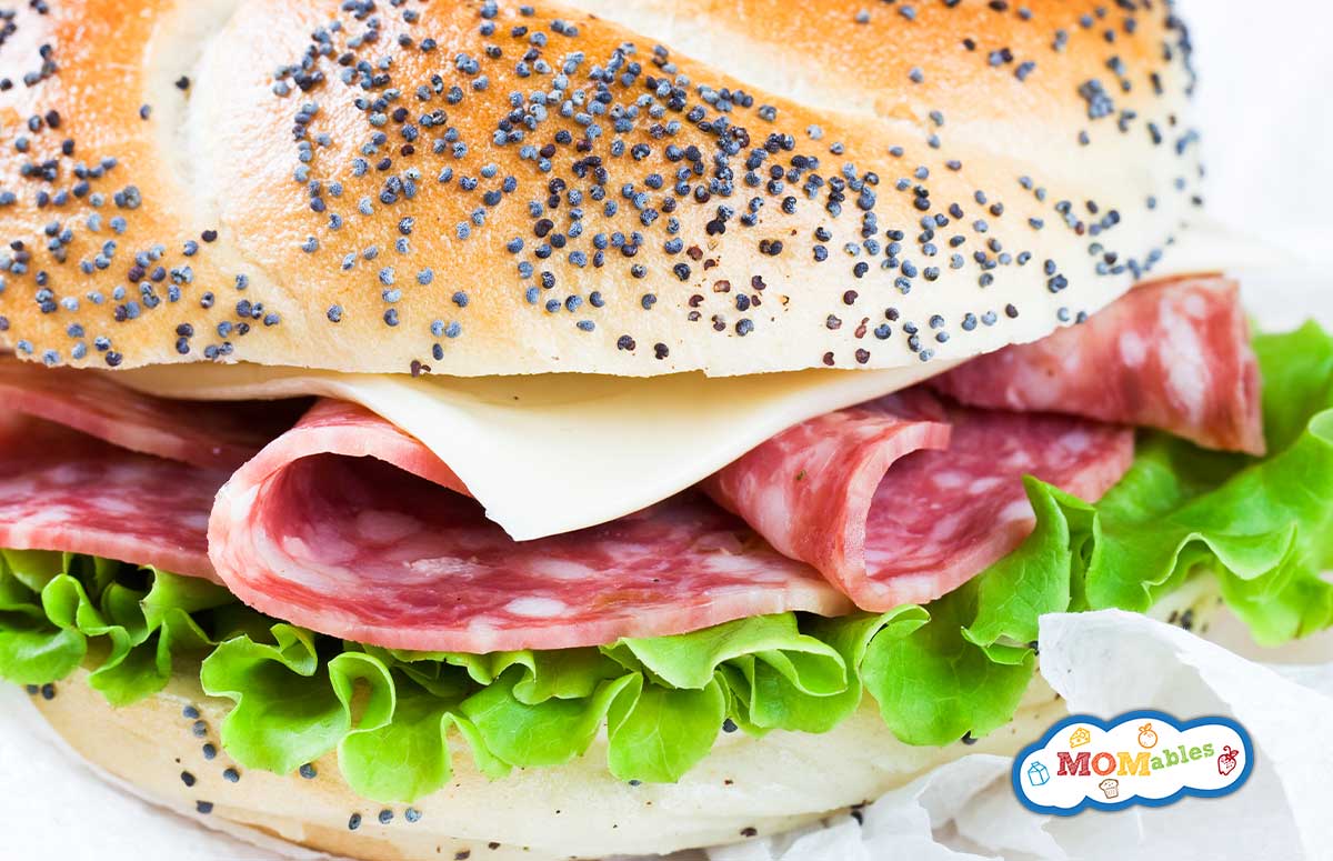 a sandwich roll topped with cheese lettuce and salamit