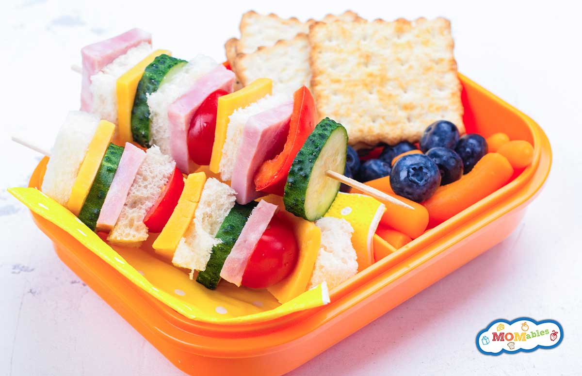 orange lunchbox with crackers, fruit and sandwich kabobs