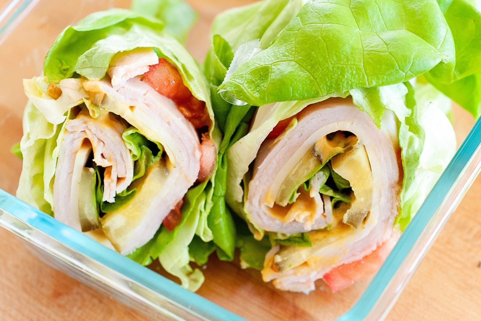 overhead view of two turkey avocado lettuce wraps in a glass lunch container