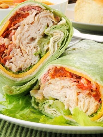 a turkey bacon wrap cut in half on a plate