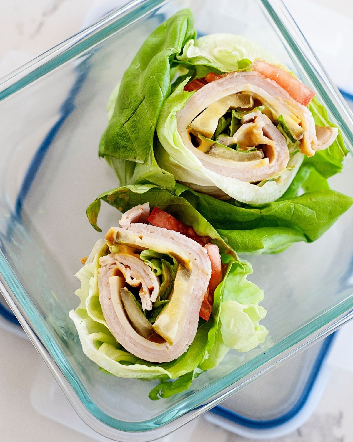 overhead view of two turkey avocado lettuce wraps in a glass lunch container