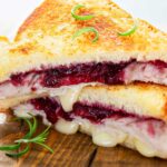 two halves of a grilled cheese sandwich with deli turkey and cranberry sauce
