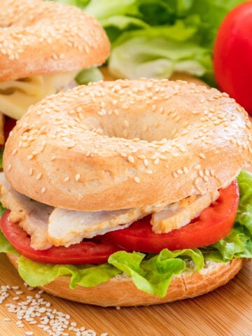 two chicken bagel sandwiches on a cutting board