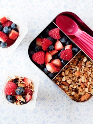 yogurt parfait in a small lunch container with mixed berries and granola