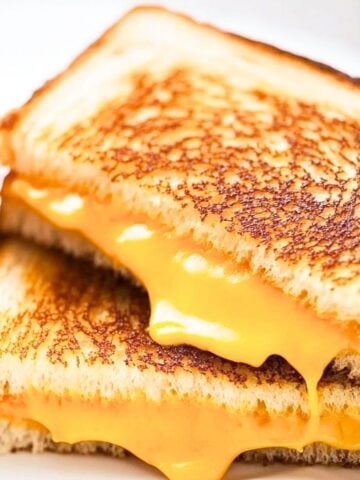 grilled cheese sandwich sliced in half with cheese oozing out.