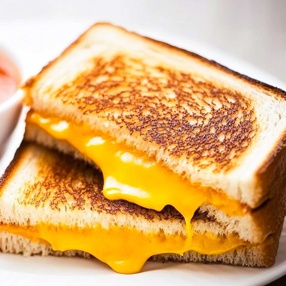 grilled cheese sandwich sliced in half with cheese oozing out.
