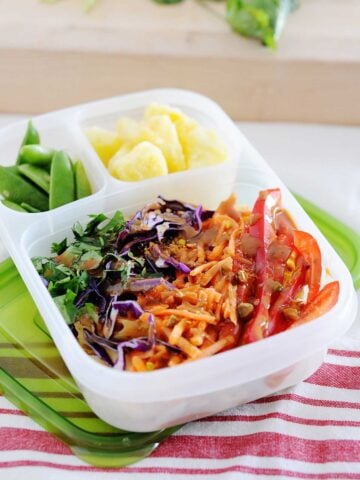 thai chicken pasta salad in a lunc container with pineapple chunks and snow peas
