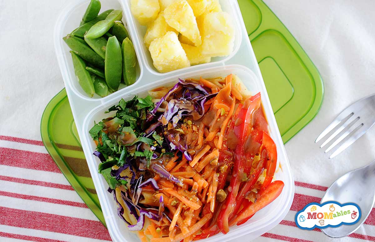 thai chicken pasta salad in a lunch container with pineapple chunks and green snow peas