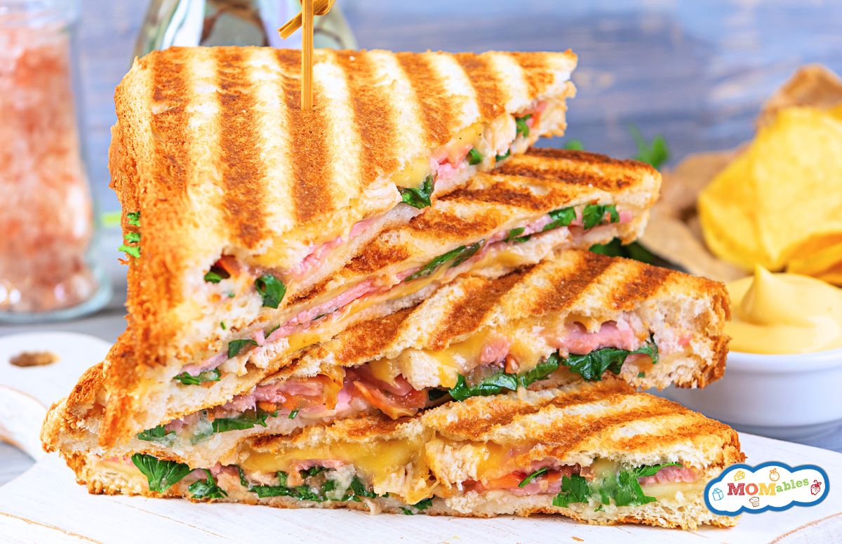 halves of a grilled ham and spinach sandwich stacked on a plate