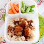 three meatballs in a lunch container with rice, and veggies