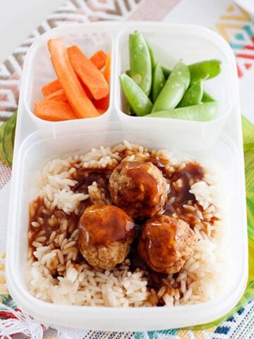 school lunch container with meatballs and rice, carrots and summer peas