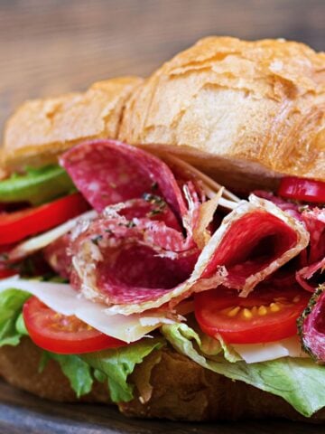 croissant sandwich with salami and vegetables