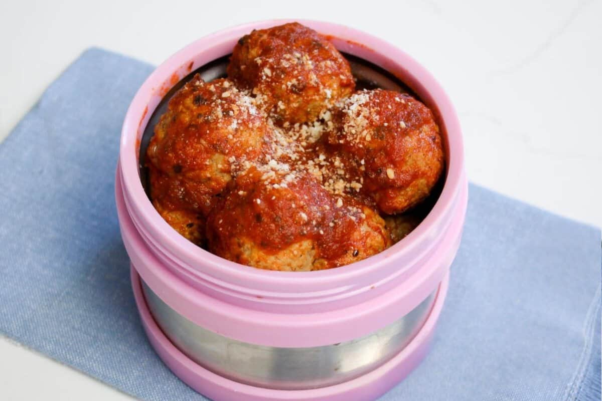 a thermos filled with hot meatballs in tomato sauce ready to be packed for school in a lunchbox