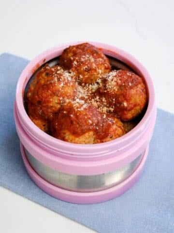 a thermos filled with hot meatballs in tomato sauce ready to be packed for school lunch