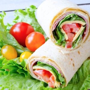 two halves of an Italian sandwich wrap with cherry tomatoes on the side