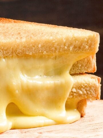 two triangle halves of a melty provolone grilled cheese sandwich, stacked