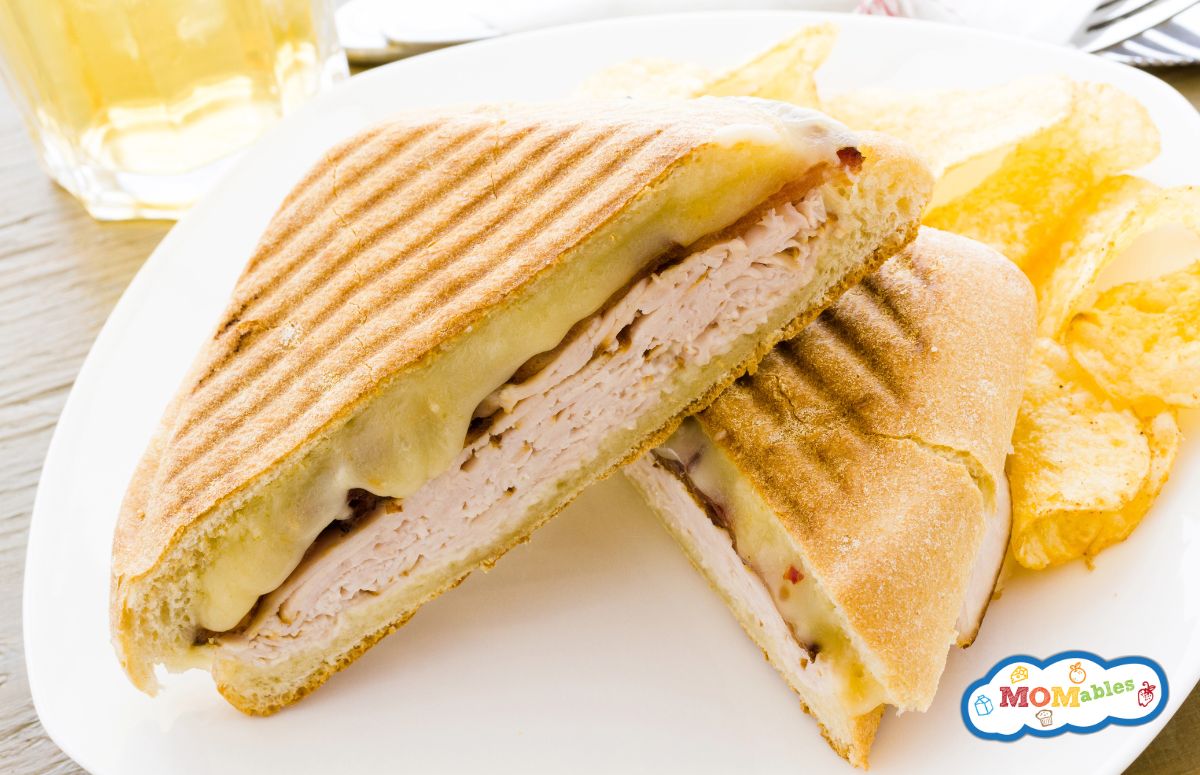 two halves of a turkey and cheese panini sandwich on a plate with chips