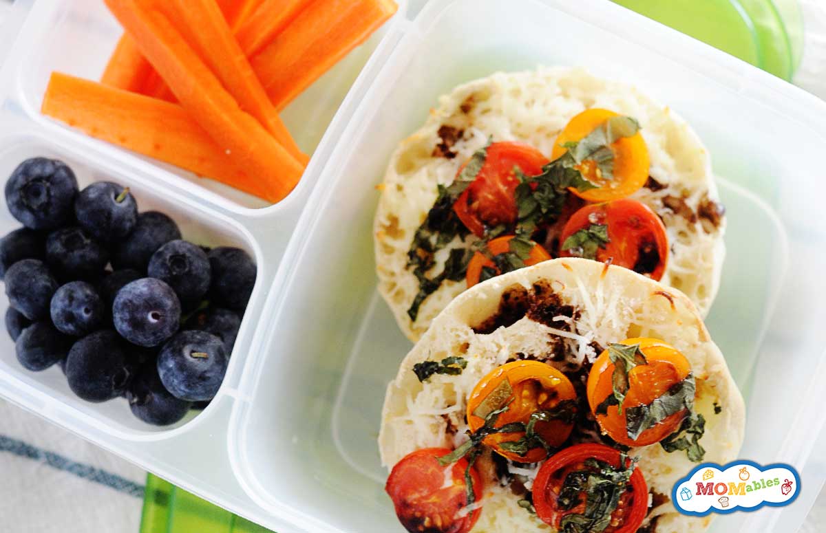 caprese english muffins in a bento box with blueberries and carrot sticks