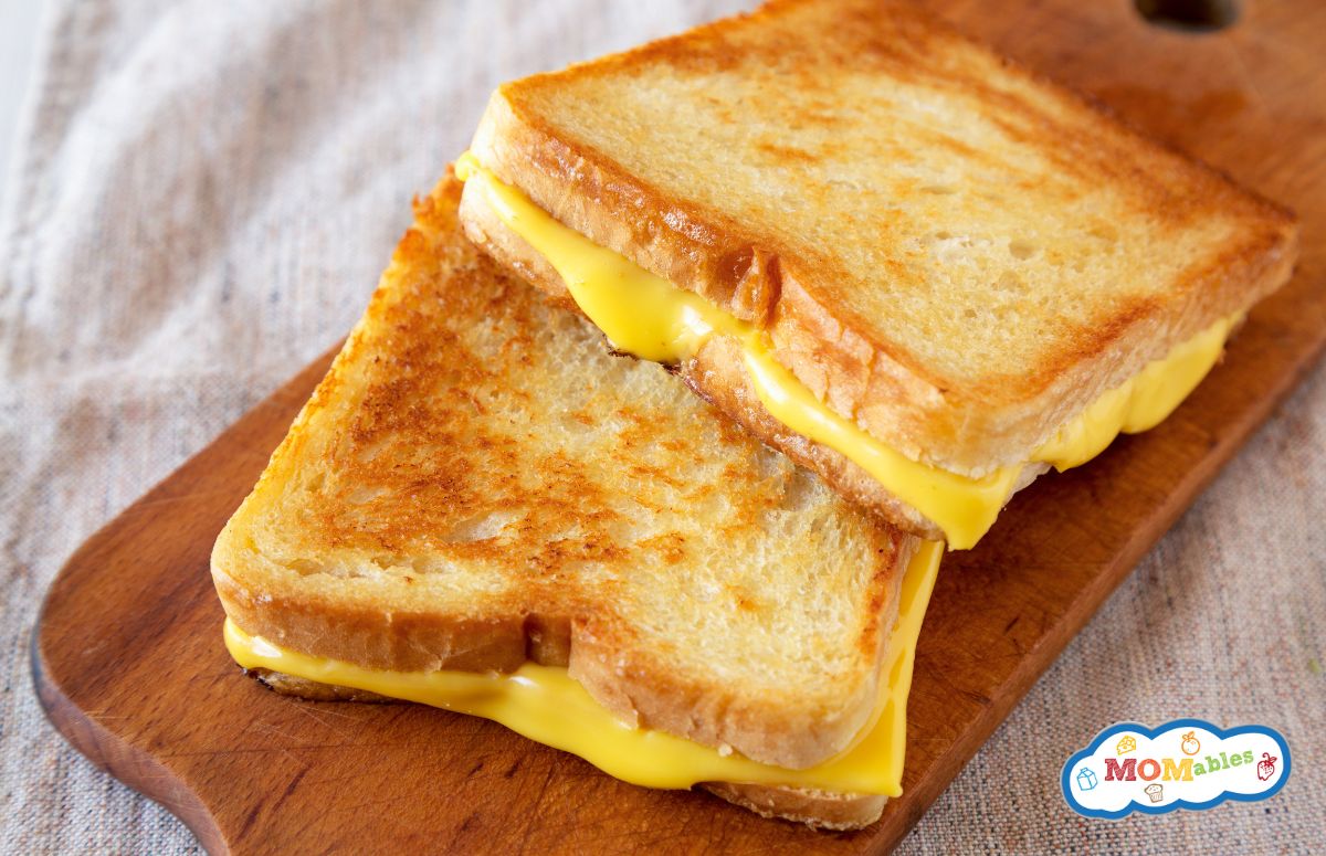 two grilled cheese sandwiches on a small wooden cutting board