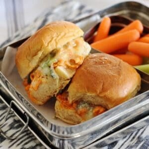 lunchbox with 2 buffalo chicken sliders and some veggies on the side